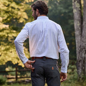 A man in a Tom Beckbe Monroe Poplin Shirt and dark pants stands outdoors, hand on hip, facing away.