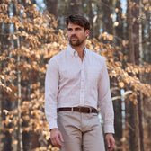 A man in a Tom Beckbe Monroe Poplin Shirt and beige pants stands outdoors before trees with brown leaves.