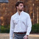 Man wearing the Tom Beckbe Monroe Poplin Shirt and gray pants outdoors with trees in the background.