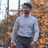 A man walks outdoors in autumn wearing the Tom Beckbe Monroe Poplin Shirt; fall foliage behind him.