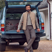 A man in a Tom Beckbe Monroe Poplin Shirt leans on a blue Land Cruiser with bags.
