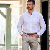 A man in a Monroe Poplin Shirt by Tom Beckbe stands outside in beige pants, hands in pockets, looking right.