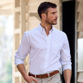 A man outdoors in a Monroe Poplin Shirt by Tom Beckbe and beige pants, gazing to his right.