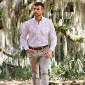 Man in a Tom Beckbe Monroe Poplin Shirt and khaki pants walks among moss-covered trees outdoors.