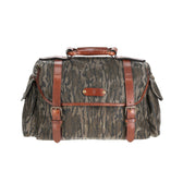 Tom Beckbes Canvas Field Bag in Mossy Oak Original Bottomland has brown leather straps and a weatherproof hood.