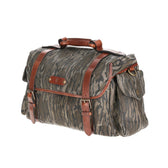 Tom Beckbes Canvas Field Bag in Mossy Oak Bottomland has leather straps, multiple pockets, and a buckle closure.