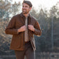 Man outdoors in a Tom Beckbe Piedmont Jacket over a plaid shirt, smiling with trees in the background.