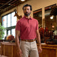 Man wearing a red polo shirt and beige pants stands inside a rustic store with leather goods and taxidermy on display.