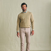 Man wearing a Tom Beckbe Foley Pima Crewneck Sweater over a collared shirt and light pants, against a plain backdrop.