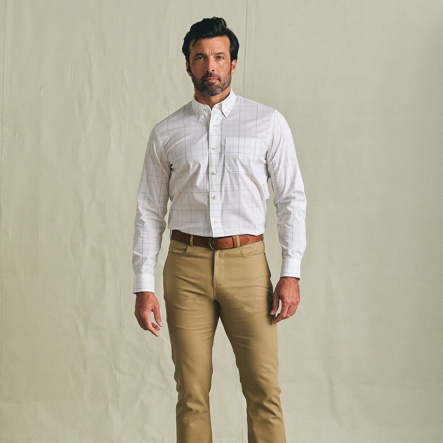 Man wearing the Tom Beckbe Powell Performance Shirt with tan pants and a brown belt against a plain background.