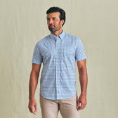 Man in Tom Beckbe Powell Performance Shirt (Short Sleeve), blue plaid, and beige pants against a plain light background.