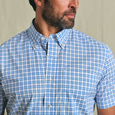 Man wearing a Tom Beckbe Powell Performance Shirt, short sleeve, in blue and white plaid, facing slightly to the side.