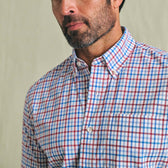 Man wearing Tom Beckbe Powell Performance Short Sleeve Shirt in red, blue, and white plaid, shown from shoulders up.
