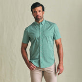 Man wears Tom Beckbe Powell Performance SS Shirt in green check, beige pants, against a light background.
