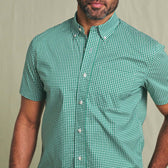 A man wears the Tom Beckbe Powell Performance Shirt, short sleeve, UPF 30+, green and white checks, plain background.