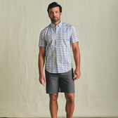 Man wearing the Tom Beckbe Powell Performance Short Sleeve Shirt, standing against a plain background with gray shorts.