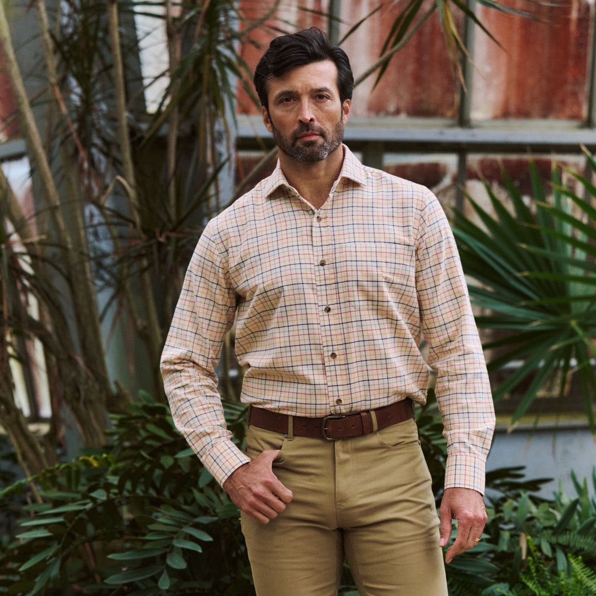 Man in a Tom Beckbe Prescott Estate Twill Shirt and tan pants, framed by greenery—ideal for your fall style.