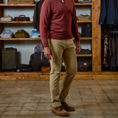 A man in a red pullover and Tom Beckbe Reid Slim-Straight Leg Cotton Chino Pant stands in a clothing store.