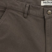 Close-up of brown Reid Shorts by Tom Beckbe with textured cotton, antique brass zip, and partially visible waistband label.