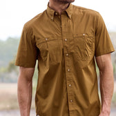 Man wearing a Tom Beckbe Tidewater Shirt (Short Sleeve) in brown, UPF 30+, two front pockets, standing outdoors.