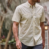 Man wearing a Tom Beckbe Tidewater Shirt (Short Sleeve) in beige with UPF 30+ coverage strolling outdoors.