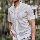 Man in a white Tom Beckbe Tidewater short-sleeve shirt with chest pockets, enjoying UPF 30+ coverage while walking outdoors.