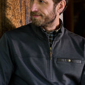 A man in a Tom Beckbe Tucker Fleece Quarter Zip stands against a wooden background, looking to the side.
