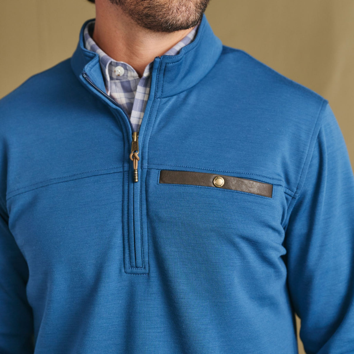 Man wears Tom Beckbe Tucker Fleece Quarter Zip over a plaid shirt, chest up, facing slightly to the side.