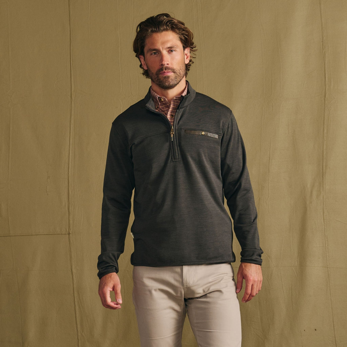 Man wears Tom Beckbe Tucker Fleece Quarter Zip and light pants, standing against a plain tan background.