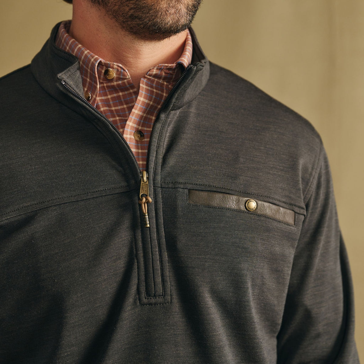 Man in Tom Beckbe Tucker Fleece Quarter Zip over plaid shirt, highlighting chest pocket and zipper detail.