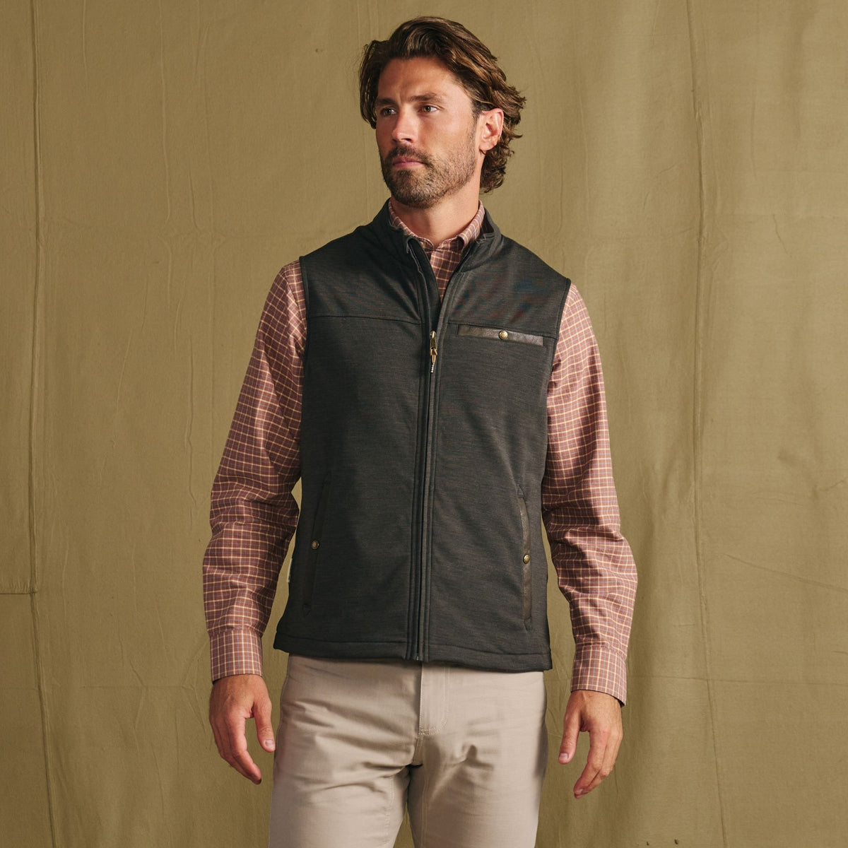 Man wears a checkered shirt, light pants, and the Tom Beckbe Tucker Fleece Vest—perfect three-season layering.