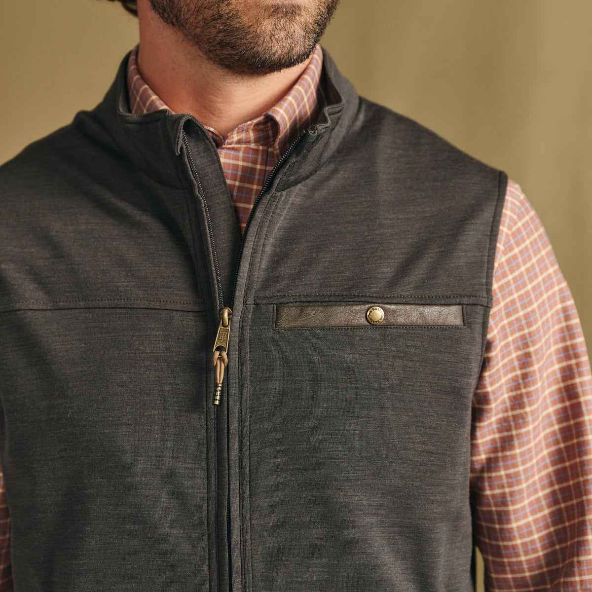 Man wearing Tom Beckbe Tucker Fleece Vest over a plaid shirt—shown shoulders to chest—a great three-season layer.