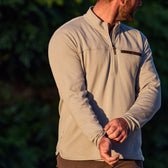 Man in a Tom Beckbe Tucker Fleece Quarter Zip, beige, glances sideways with a blurred outdoor backdrop.