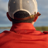 A person in a red shirt and beige mesh cap enjoys thermal insulation outdoors with Tom Beckbes Tucker Fleece Quarter Zip.