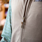 Close-up of a zipped beige vest worn over a green and white checkered shirt.