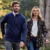 A man and woman walk outdoors, smiling. Hes in a blue Tom Beckbe Warren Fleece; she wears a camouflage jacket.