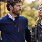 Man in a Warren Fleece Quarter Zip and woman in camouflage stand outdoors with trees and thermal insulation behind them.
