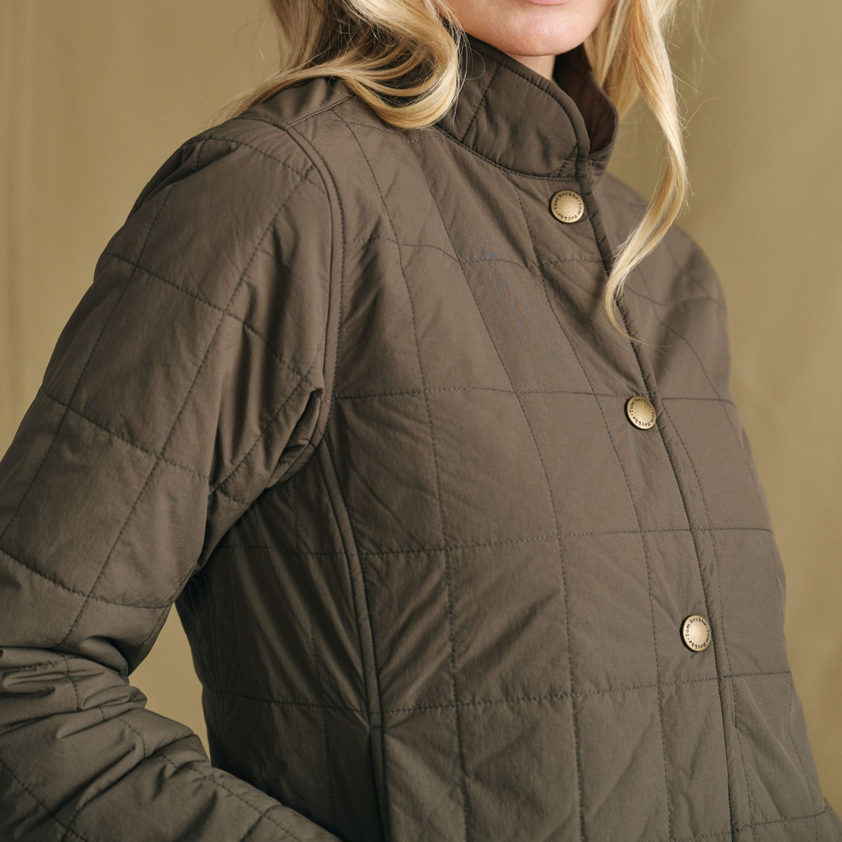 Model wearing Tom Beckbe Women’s Tyler Quilted Jacket with gold buttons and Repreve, posed against a plain backdrop.