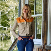 Person near a window in Tom Beckbe Womens Uplander Shirt and blue jeans, hands in pockets, outdoors by woods.