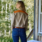 On a wooden porch, someone wears the Womens Uplander Shirt by Tom Beckbe with blue jeans from the womens field collection.