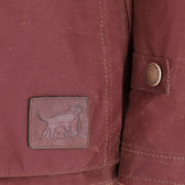 Close-up of the Women's Fox Red Blakeley Jacket by Tom Beckbe, featuring waxed cotton and a dog leather patch.