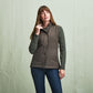 Woman in Tom Beckbe Womens Tyler Quilted Vest over a sweater and jeans, standing against a plain light backdrop.