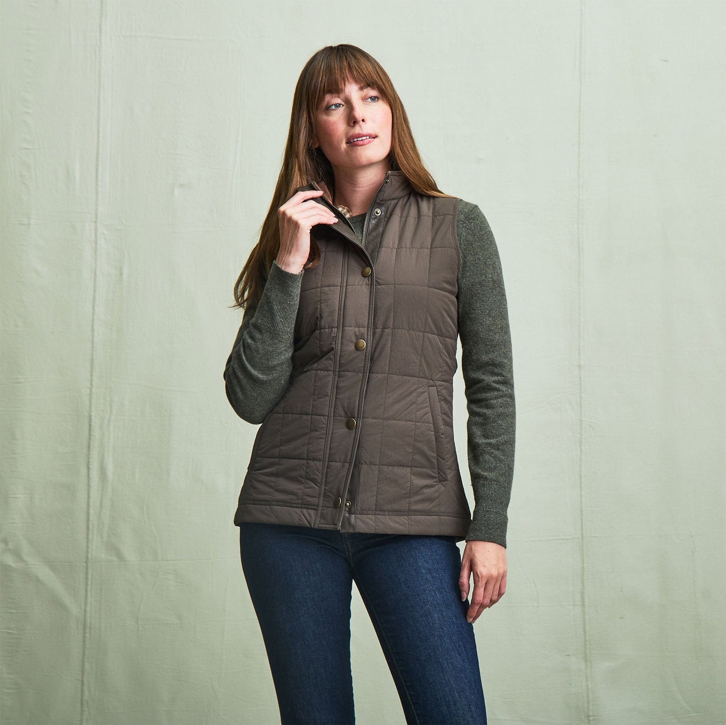 Woman in Tom Beckbe Womens Tyler Quilted Vest over a sweater and jeans, standing against a plain light backdrop.