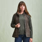 Woman wearing the Tom Beckbe Womens Tyler Quilted Vest over a green sweater and jeans, against a light background.