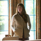Woman with long hair wears the Tom Beckbe Womens Tyler Quilted Vest, standing indoors by a sunlit window with patterned curtains.