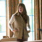 A woman wears the Tom Beckbe Womens Tyler Quilted Vest indoors, hands in pockets, before patterned curtains and windows.