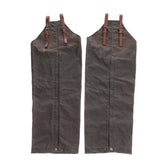 Tom Beckbe Waxed Canvas Chaps in brown with leather straps and buckles, shown on a white background.