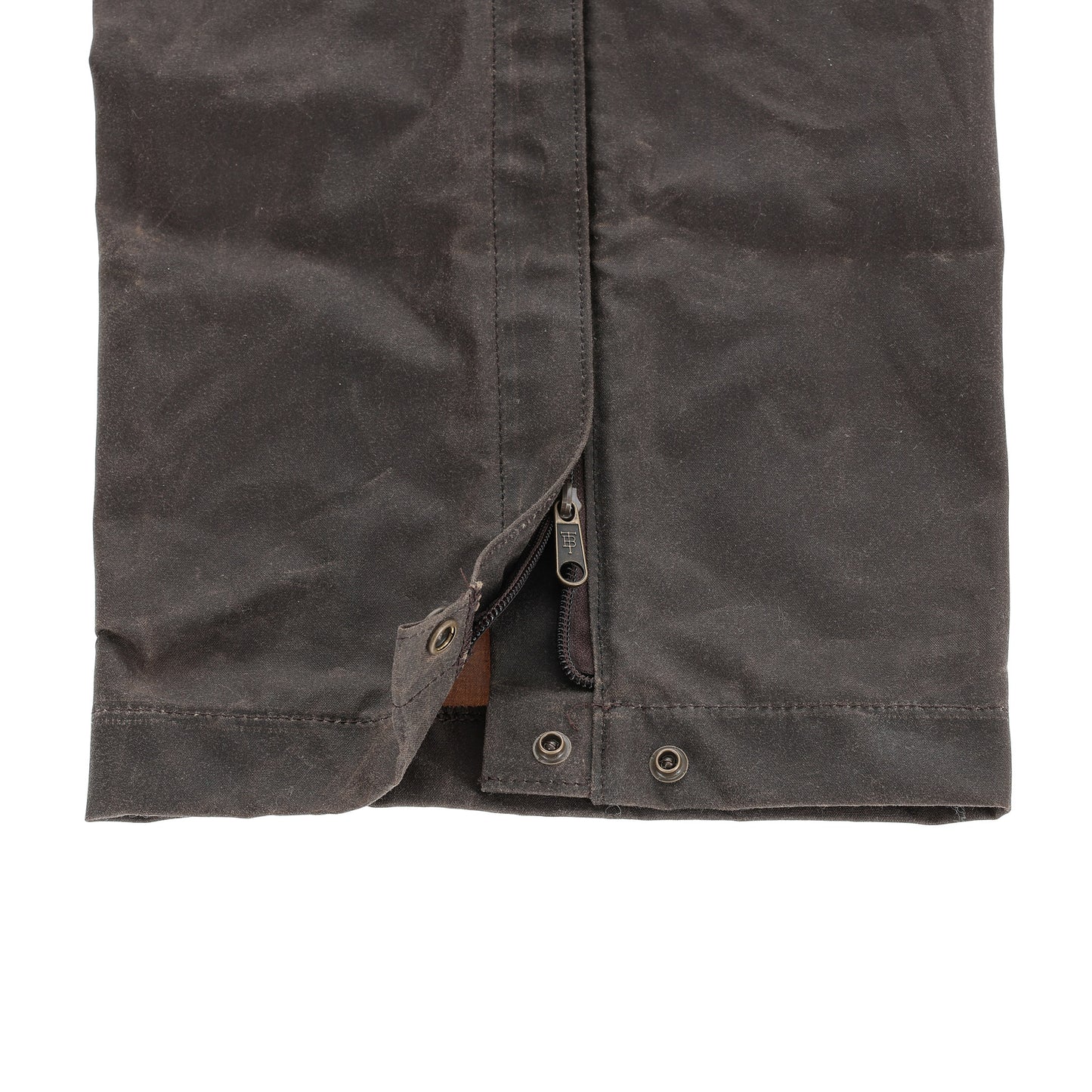Close-up of the Tom Beckbe Waxed Canvas Chaps hem with zipper and snap button closures.