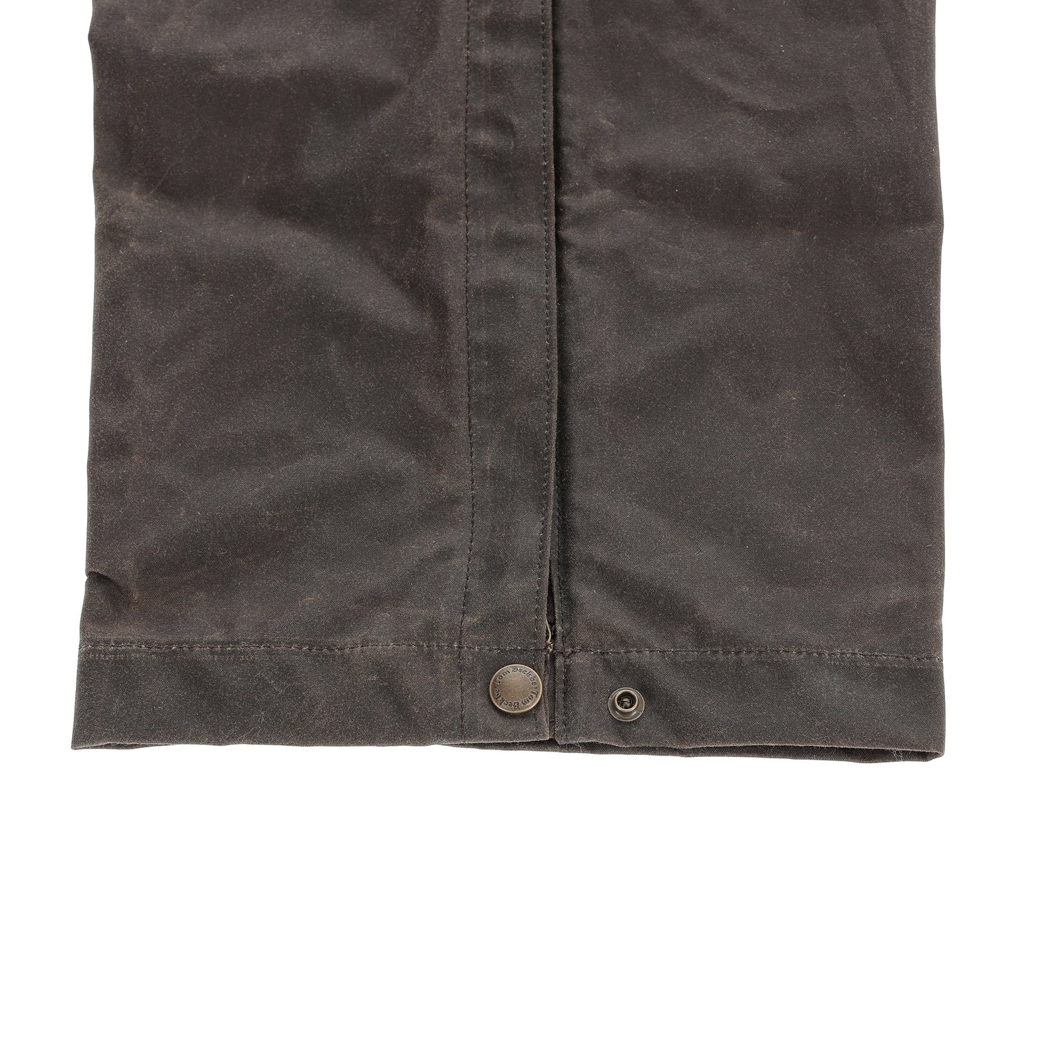 Close-up of Tom Beckbe Waxed Canvas Chaps featuring snap buttons and weather-resistant brown fabric.