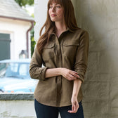 Woman by a white wall in a Tom Beckbe Womens Mackay Moleskin Shirt and dark jeans, blue car in background.